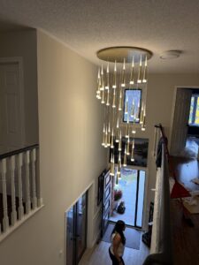 Modern gold chandelier installation in grand foyer by AMM Electric